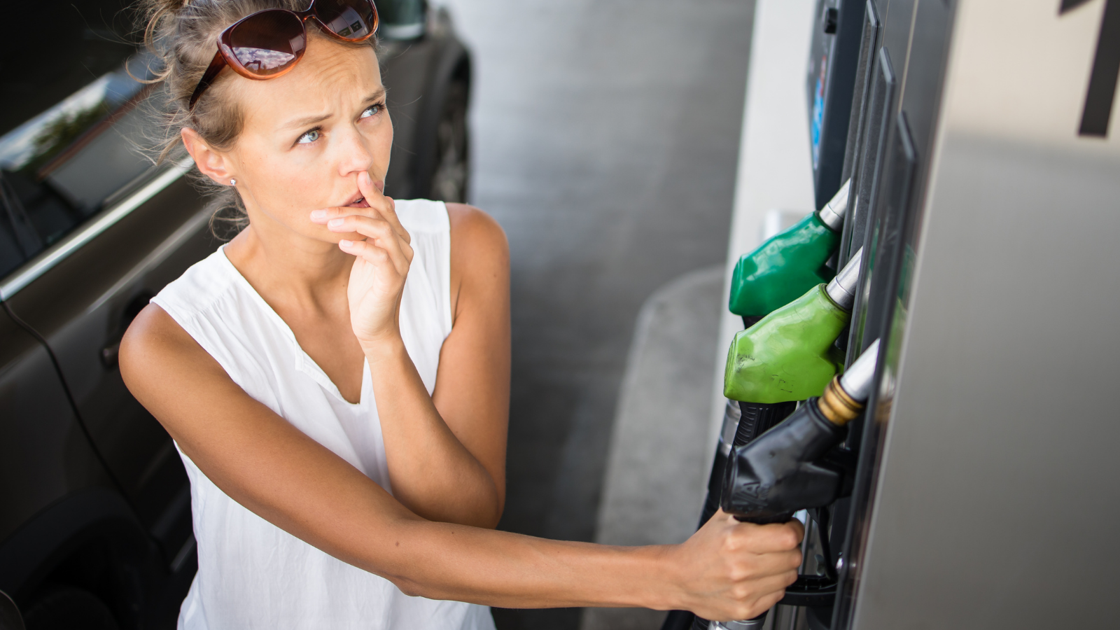Woman standing at gas pump looking inquisitive