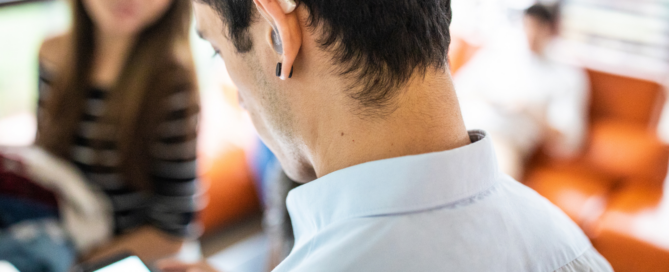 Close up of man with hearing aid in his ear looking down