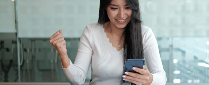 Woman with an excited expression looking down at smartphone in her hand