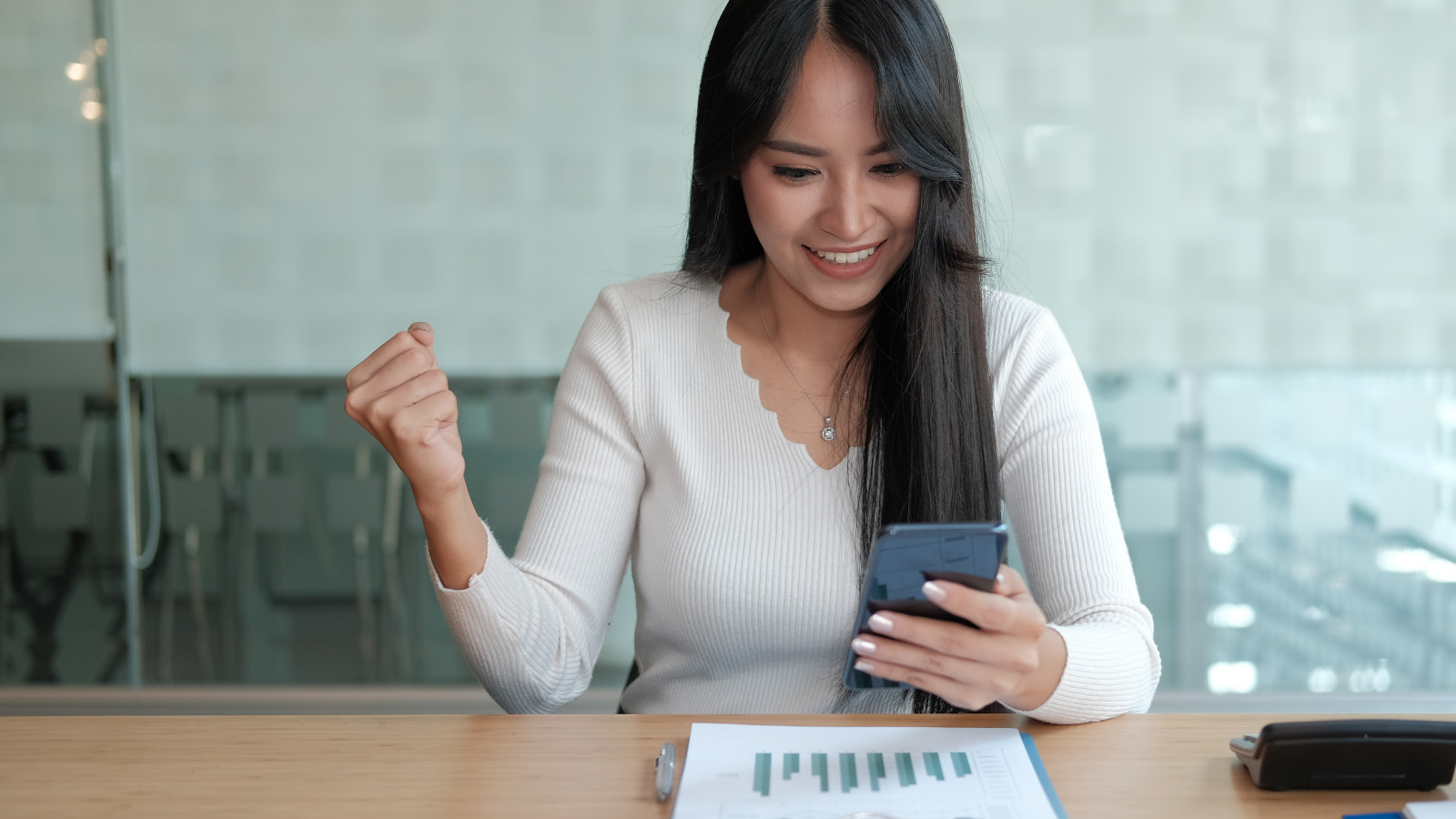 Woman with an excited expression looking down at smartphone in her hand